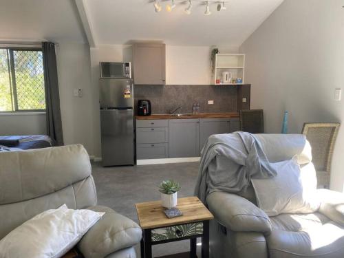 ein Wohnzimmer mit zwei Stühlen und eine Küche in der Unterkunft Rosehill cottage and bush retreat in Glastonbury