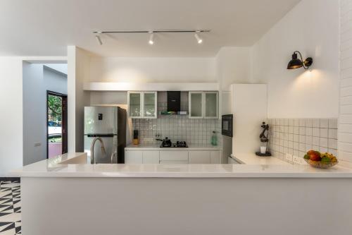 a kitchen with white counters and a refrigerator at La Masillia, 2 BHK with Private Pool, 15 mins from Morjim Beach, Wifi, Peaceful location, Kitchen, Security, Patio in Siolim