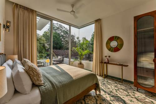 a bedroom with a bed and a large window at La Masillia, 2 BHK with Private Pool, 15 mins from Morjim Beach, Wifi, Peaceful location, Kitchen, Security, Patio in Siolim