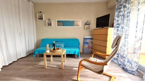 un salon avec un canapé bleu et une table dans l'établissement Vaux sur Mer - EMPLACEMENT de CHOIX - APPARTEMENT - PLAGE de NAUZAN, à Vaux-sur-Mer