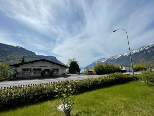 a building on a road with mountains in the background at Bergblick Apartments - Weisshorn in Brienz