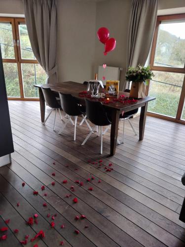 a dining room table with red rose petals on the floor at La Merveilleuse by Infiniti hôtel in Dinant