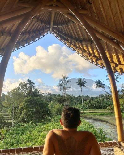 a man sitting in a hut looking at the sky at Wiwaka Harmony in Nature in Selat
