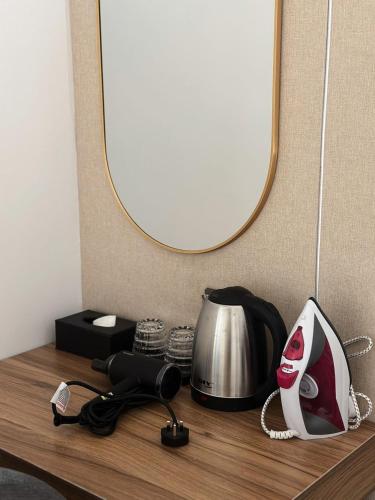 a table with a mirror and a phone and a tea kettle at Hotel Ivory Papar in Papar
