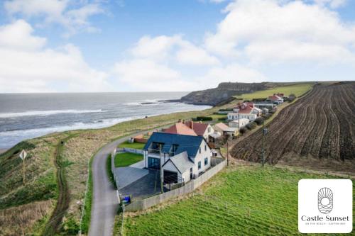 an aerial view of a house on a hill next to the ocean at Luxury 4-Bedroom Beachfront Home with Hot Tub & Games Room in Cayton