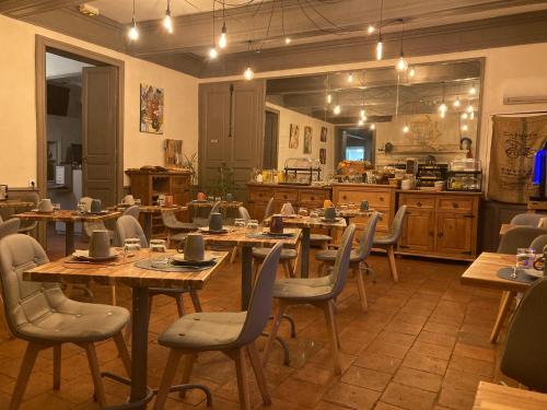 Un restaurante con mesas y sillas de madera y una cocina. en Logis Domaine de Peyrolade, en Daux