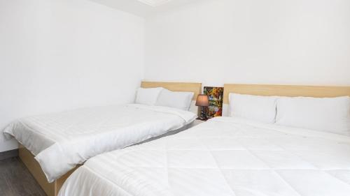 two beds in a hotel room with white sheets at STAR BAY Residence Sihanoukville - 400m to Sokha Beach in Sihanoukville