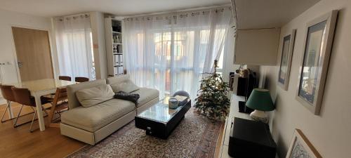 a living room with a white couch and a christmas tree at Chic & Cosy apartment - 60m2, 3 rooms in Asnières-sur-Seine