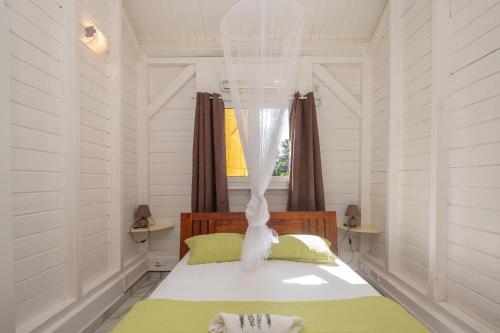 a bedroom with white walls and a bed with a window at L’Escale Kreyol - Avec jacuzzi in Lamentin