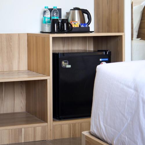 a small black refrigerator in a wooden cabinet at Akoya Business Hotel Hyderabad Airpot in Shamshabad