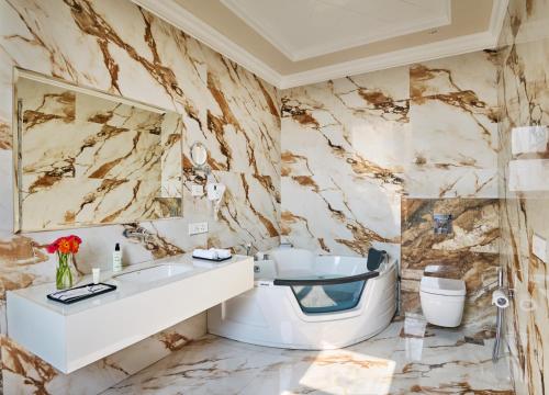 a marble bathroom with a sink and a toilet at Royal Kingdom Sarovar Portico Pilibhit in Pīlībhīt