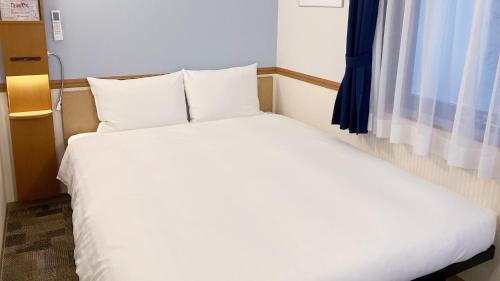 a bedroom with a white bed and a window at Toyoko Inn Kurashiki-eki Minami-guchi in Kurashiki