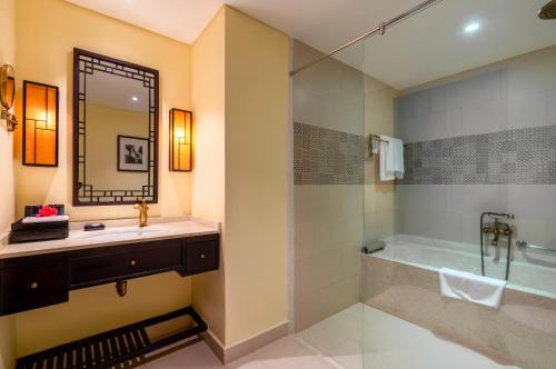 a bathroom with a sink and a tub and a mirror at Wyndham Garden Hoi An Cua Dai Beach in Hoi An