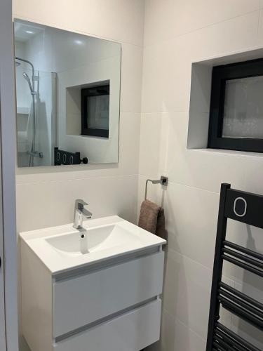 une salle de bain blanche avec un lavabo et un miroir dans l'établissement Cocon proche de Lyon, à Neyron