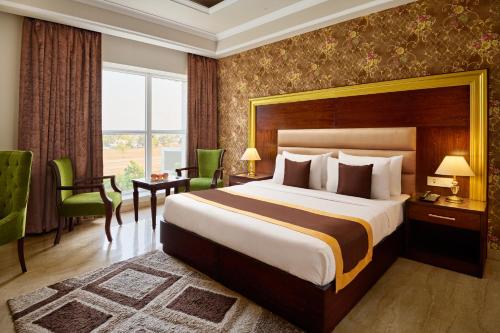 a hotel room with a bed and a desk and chairs at Royal Kingdom Sarovar Portico Pilibhit in Pīlībhīt