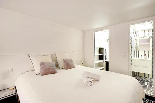 - une chambre blanche avec un grand lit blanc et 2 oreillers dans l'établissement Appartement Montmartre, à Paris
