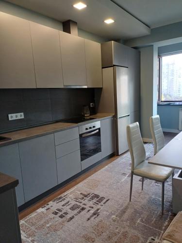 Una cocina con gabinetes blancos y una mesa y sillas. en Apartment green park, en Chişinău