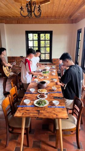 a group of people standing around a table with food at Rosa Homestay in Ấp Trạm Hành