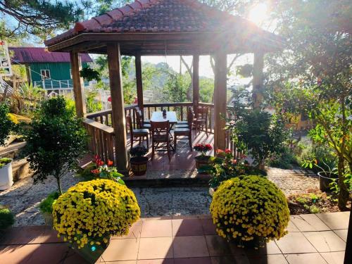 a gazebo with a table and chairs in a garden at Rosa Homestay in Ấp Trạm Hành