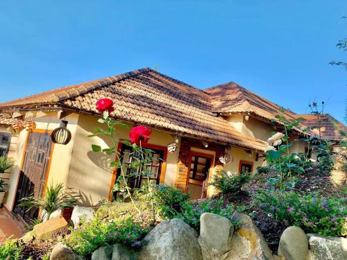 a house with red roses in front of it at Rosa Homestay in Ấp Trạm Hành