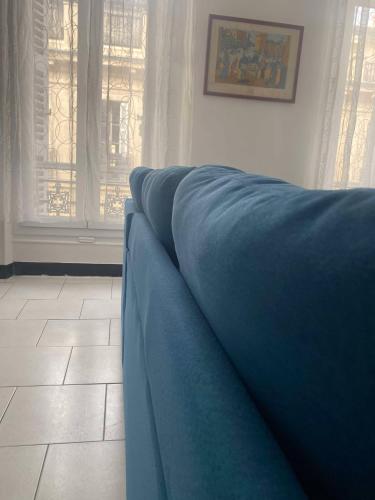 - un canapé bleu dans le salon avec fenêtres dans l'établissement Joli T2 refait à neuf, lumineux et accessible, à Marseille