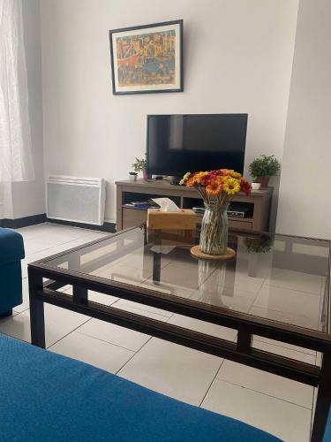 un salon avec une table avec un vase de fleurs dans l'établissement Joli T2 refait à neuf, lumineux et accessible, à Marseille