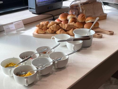 a counter with bowls and plates of food and bread at Aank Hotel Incheon Guwol in Incheon