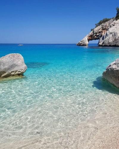 a beach with rocks and blue water and blue sky at Sea Breeze Home in Lotzorai