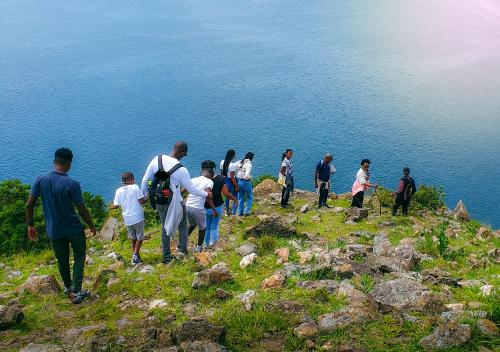 a group of people standing on a hill near the water at Umutuzo Lodge Kivu Lake in Buhoro