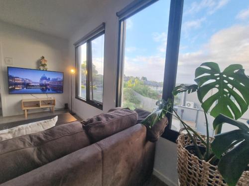 a living room with a couch and a large window at Luxurious stay at Doncaster East in Doncaster East