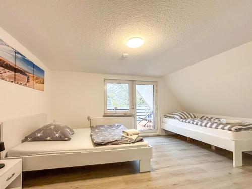two beds in a room with a window at Ferienhaus am Deich mit Küche, Balkon und Smart-TV in Emden