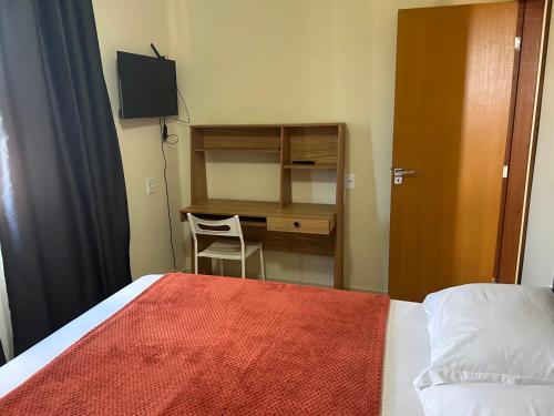 a bedroom with a desk and a bed with a red blanket at Chalé 4 vista para montanha in Penedo