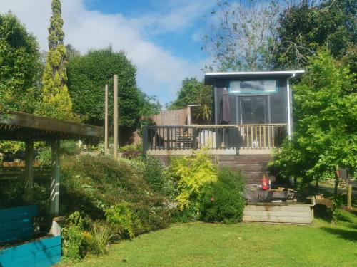 a cottage in a garden with a porch at starry nights tree house in Waikino