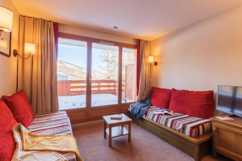 a living room with a couch and a large window at Résidence Pierre & Vacances l'Albane in Vars