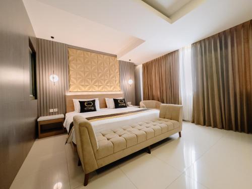 a bedroom with a large bed and a couch at El Cavana Bandung in Bandung