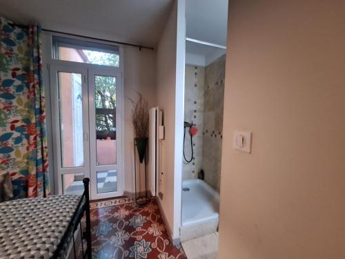 La salle de bains est pourvue d'une baignoire, d'une douche et d'une fenêtre. dans l'établissement La maison rose, à Avignon