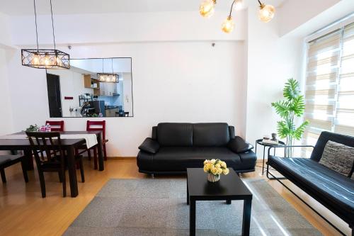 a living room with a black couch and a table at Premium 1BR unit at The Avant in Manila