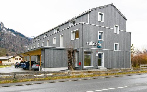 a gray building with a store on the side of a street at Cubilaris Motel in Bad Ragaz