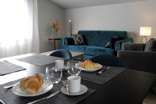 - une table avec deux assiettes de croissants et des verres à vin dans l'établissement Appartement duplex centre historique avec patio, à LʼIsle-sur-la-Sorgue