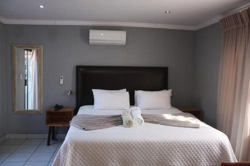 a bedroom with a bed with two towels on it at On Hill Lodge in Bloemfontein