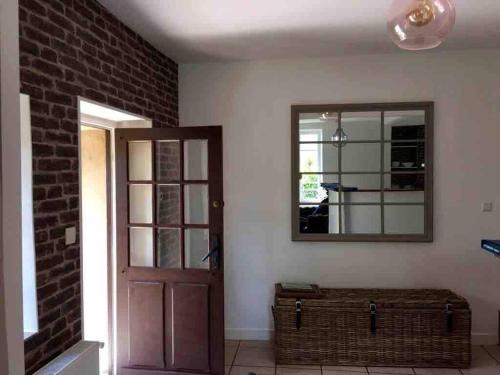 a room with a door and a mirror and a brick wall at Gîte La Maisonnette à Auvers-sur-Oise in Auvers-sur-Oise