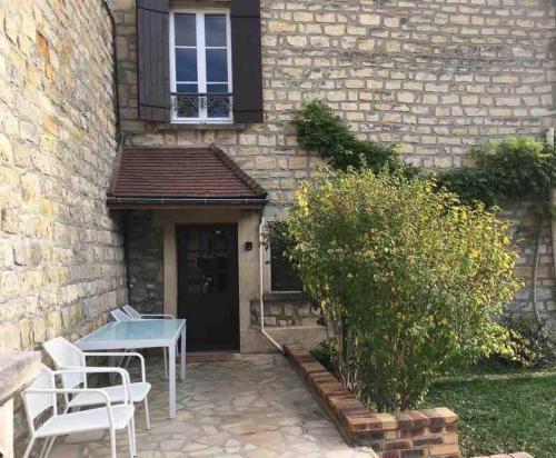 a patio with a table and chairs in front of a building at Gîte La Maisonnette à Auvers-sur-Oise in Auvers-sur-Oise