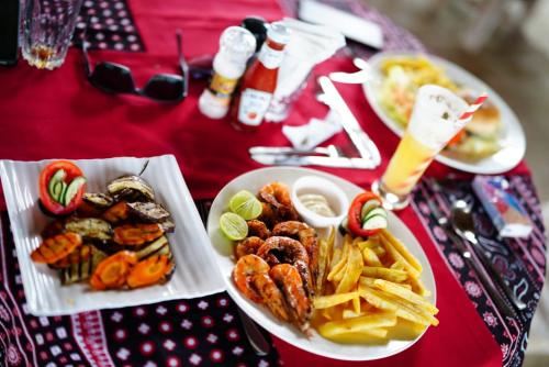 a table with two plates of food and french fries at Kirepwe Ecco Camp Watamu in Watamu
