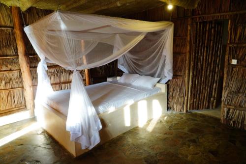 a bedroom with a bed with a mosquito net at Kirepwe Ecco Camp Watamu in Watamu