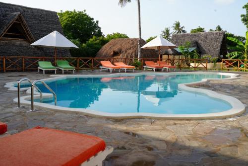 a pool at a resort with chairs and umbrellas at Kirepwe Ecco Camp Watamu in Watamu