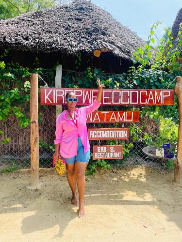 a woman is standing in front of a sign at Kirepwe Ecco Camp Watamu in Watamu