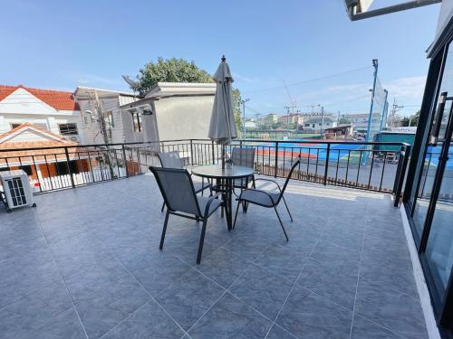 une table et des chaises sur un balcon avec un parasol dans l'établissement AnJia Villa, à Pattaya (sud)