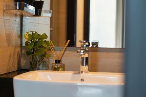 a bathroom sink with a vase of flowers and a mirror at DingD0ng Home FelizEnVista 5-star facilities in Ho Chi Minh City