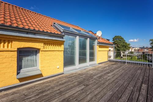 a large wooden deck with a yellow house at Centralapartment J3 in Schwerin