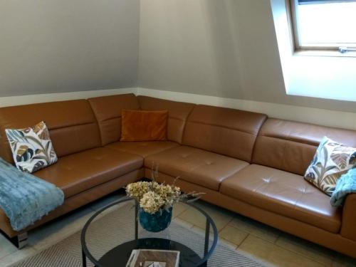 a brown leather couch in a living room with a glass table at Maya Apartman in Szeged